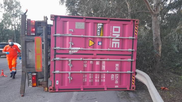 Camión con contenedor volcado junto a la carretera