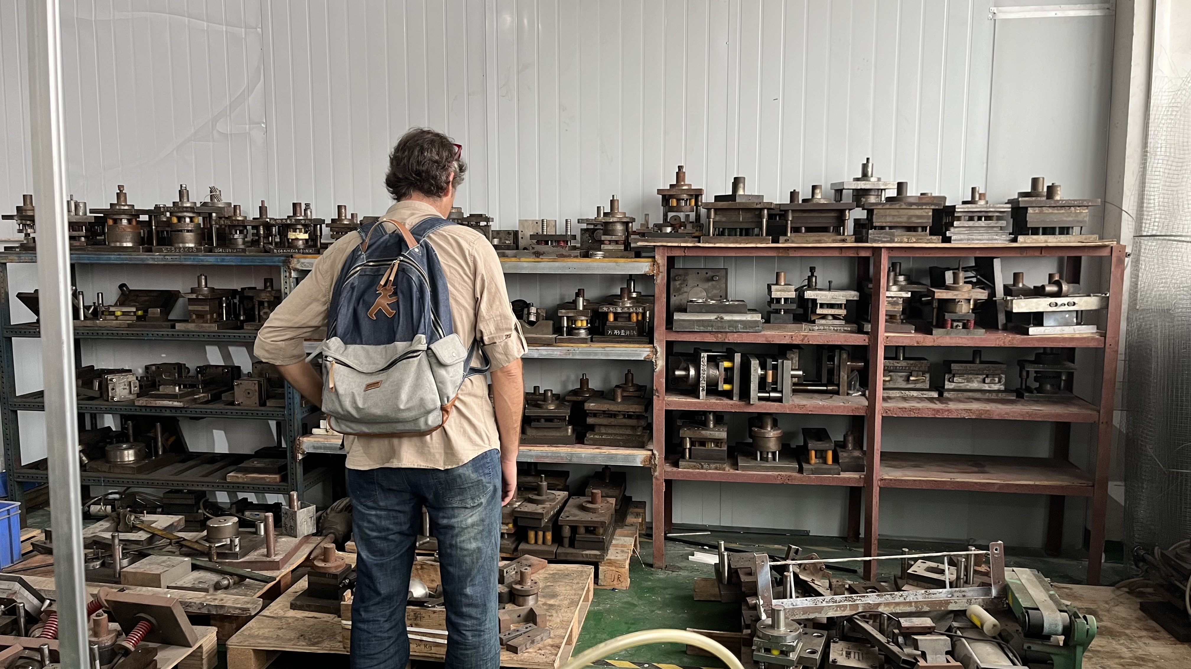Dani observando una estantería de moldes en una fábrica